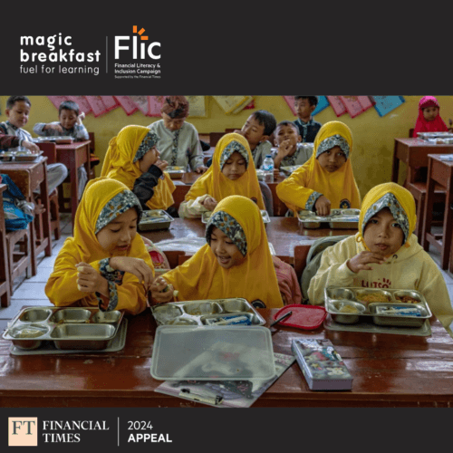 Indonesian schoolchildren sit in rows of three at their school desks, smiling while they eat their food, provided by the new programme aiming to transform the health and educational outcomes of children.